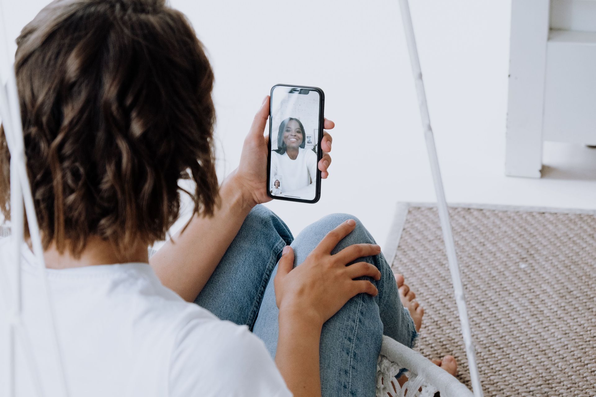 Person sitting on stairs, looking at a smartphone showing a video call.