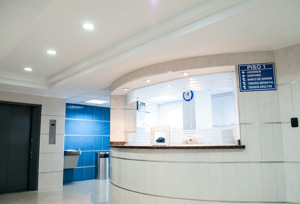 Bright white hospital reception desk with blue wall panels and waiting area seating