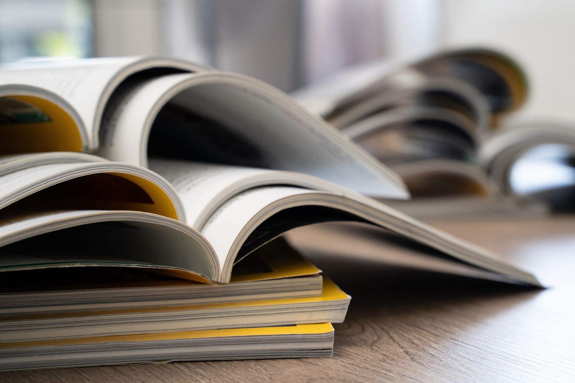 Open magazines fanned out on a table, with yellow-edged pages visible.