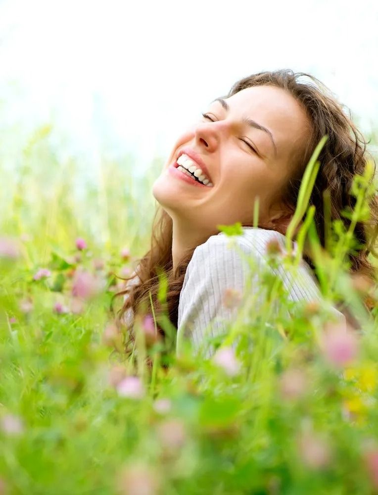 Woman Smiling and Relaxing in A Field of Green Grass and Flowers, Eyes Closed — The Colonic Coach in Gulliver, QLD