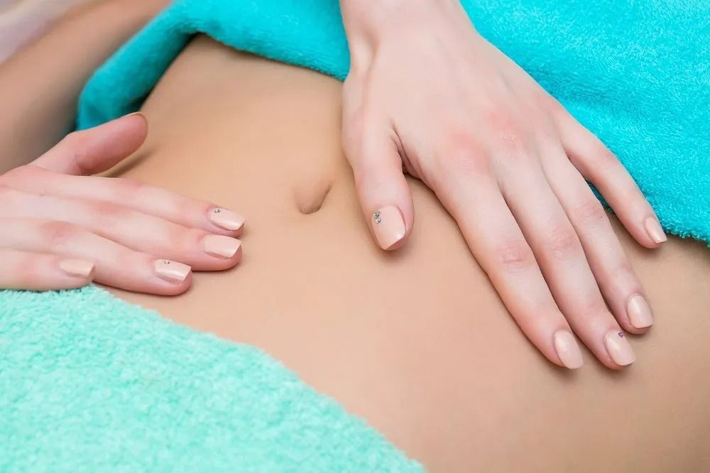 Hands Gently Massaging a Person's Abdomen, Turquoise Towel Visible — The Colonic Coach in Gulliver, QLD