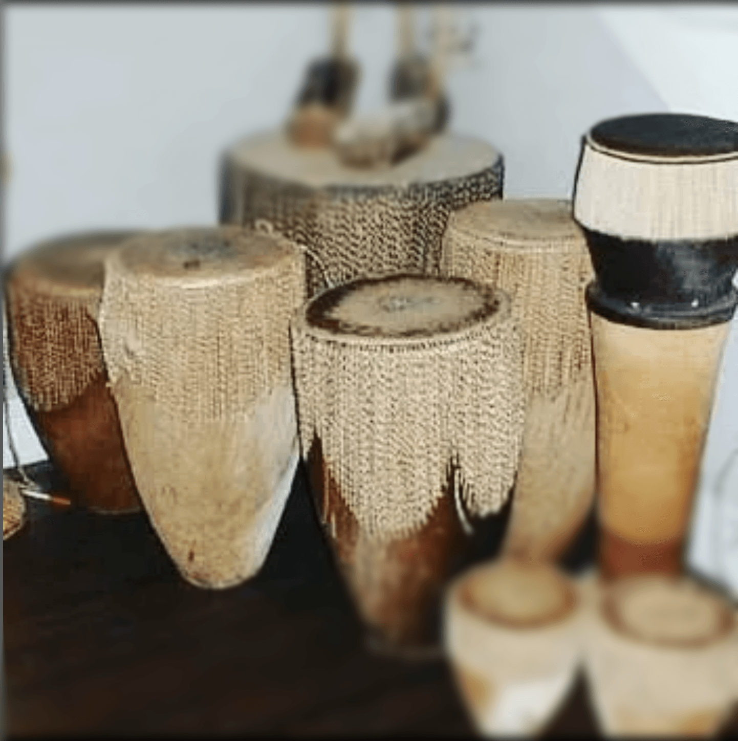 A group of ganda wooden drums are lined up on a table