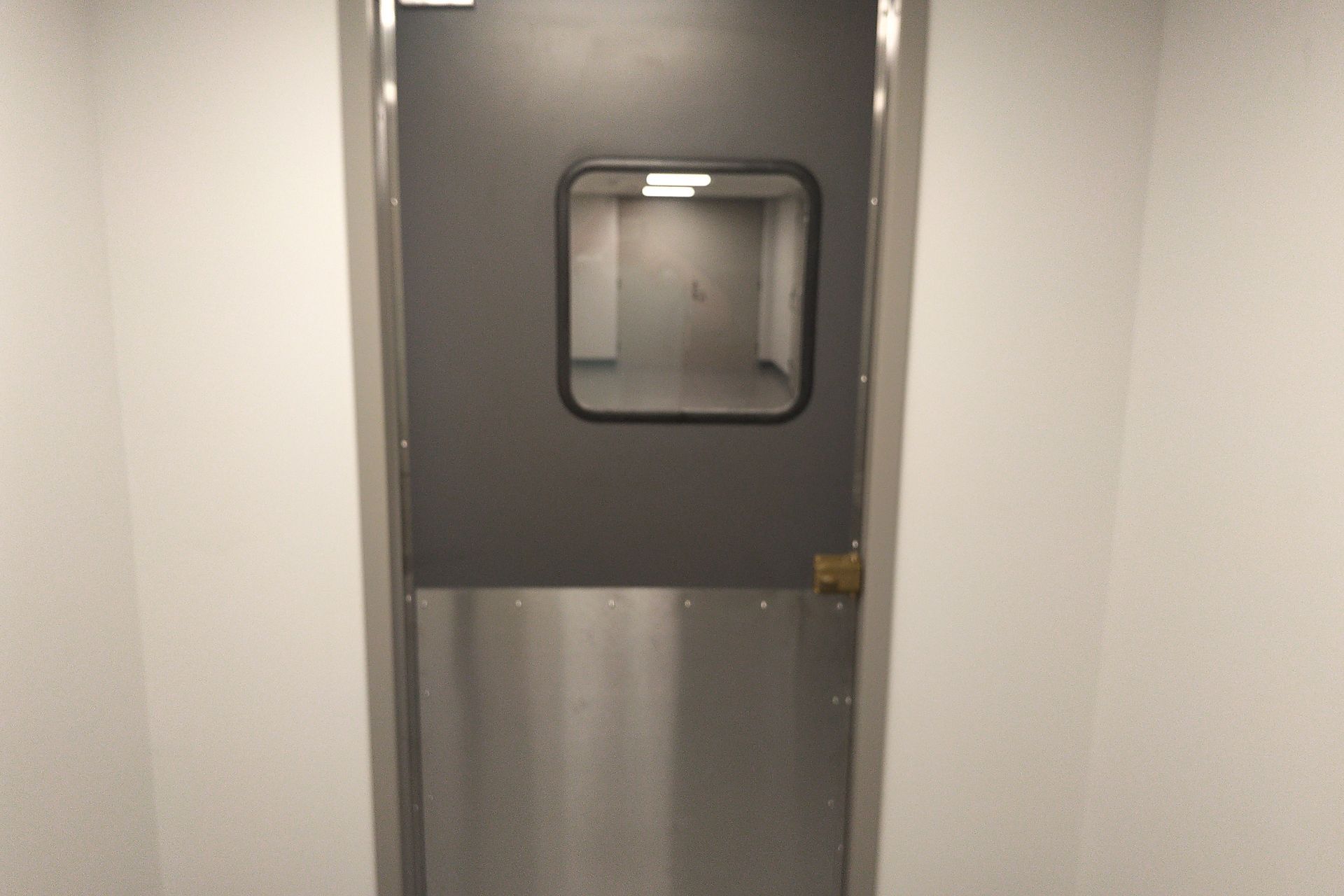 A stainless steel door with a window in a hallway.