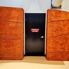 A black door with a red sign on it that says emergency exit