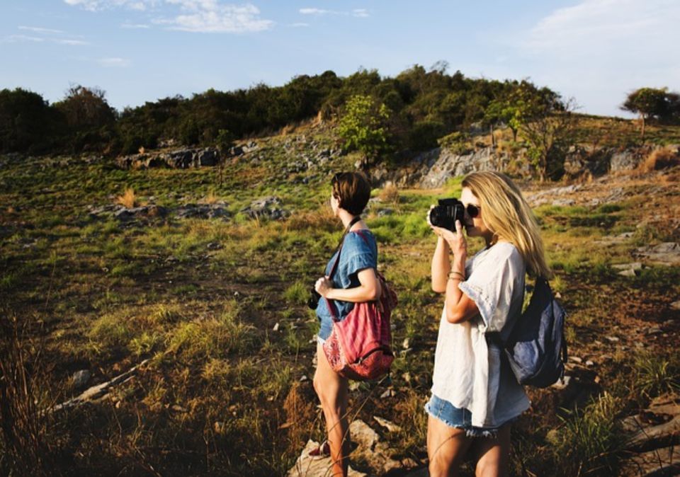 Due donne con gli zaini esplorano un paesaggio roccioso, una delle quali scatta una foto.