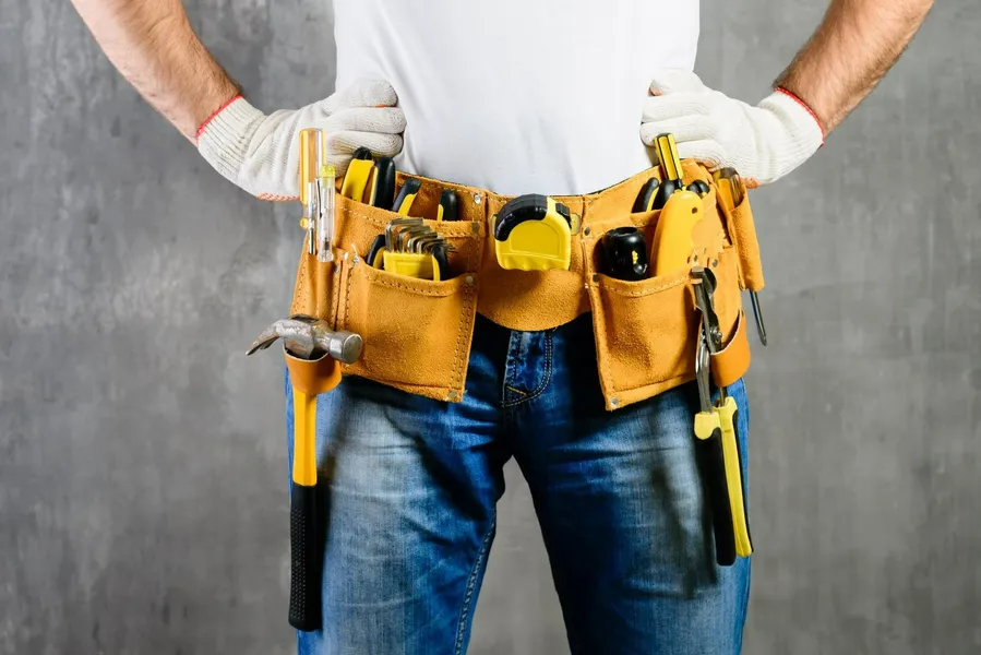 A man is wearing a tool belt with tools in it.