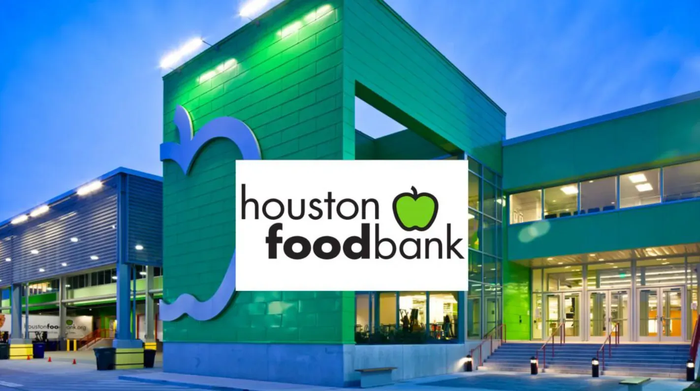 Group of people posing in front of the Boston Food Bank logo wall in a bright lobby