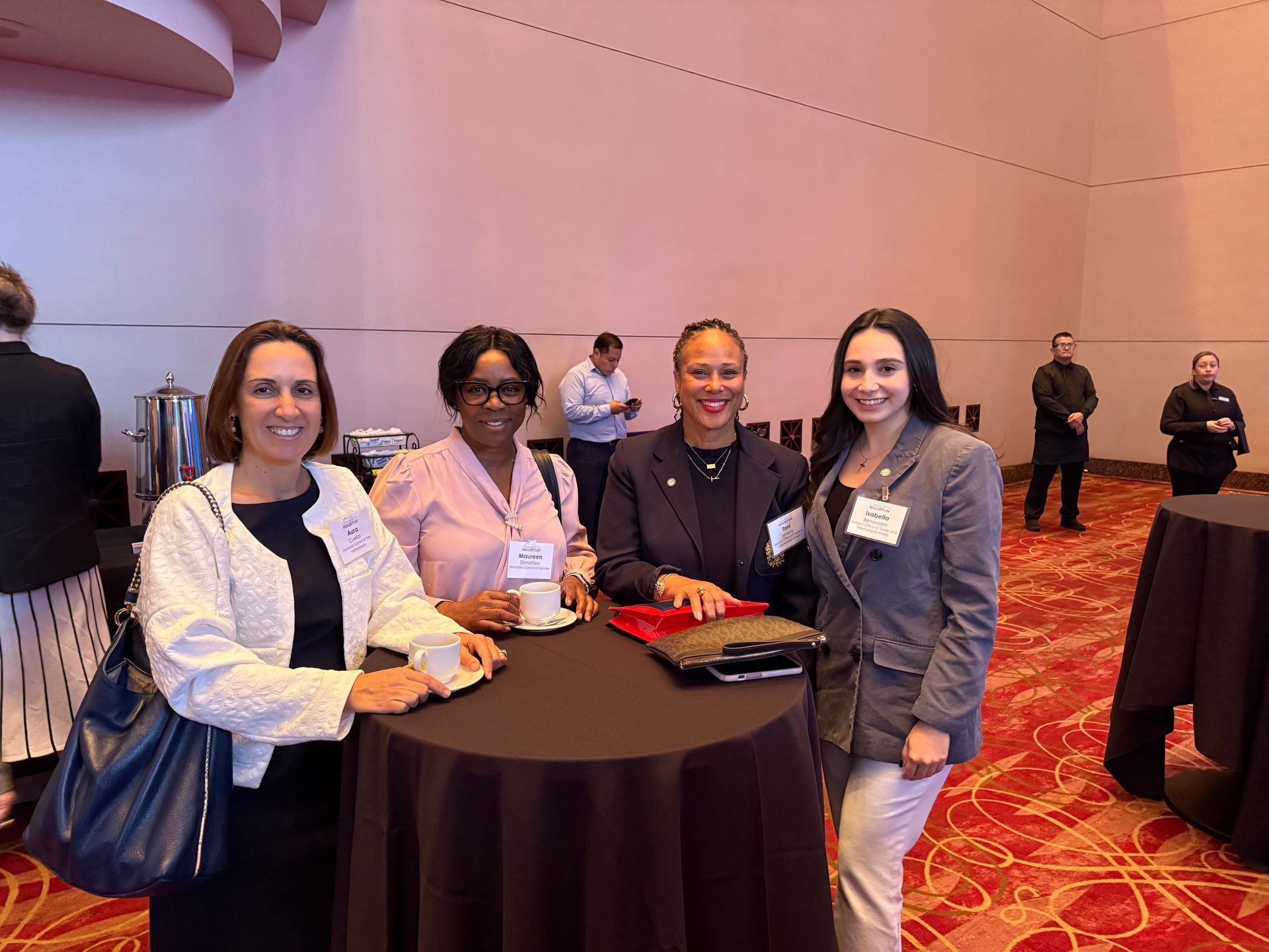 Four people stand around a high-top table at a professional conference in a large, carpeted ballroom.