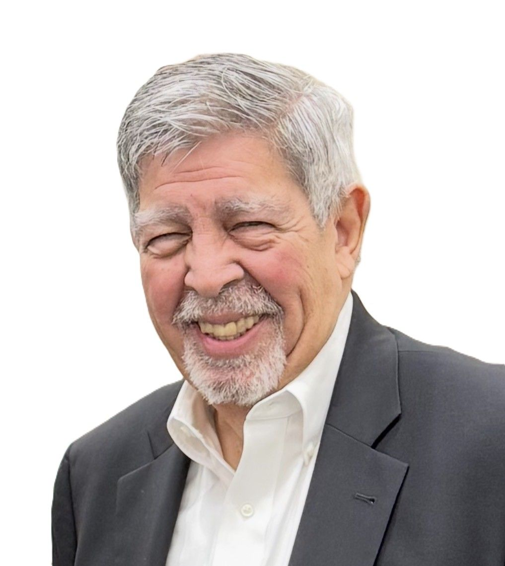 A professional headshot of a person with short hair and glasses, wearing a dark suit, white shirt, and navy blue tie.