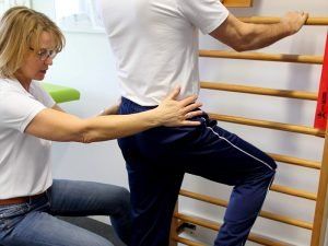 Eine Frau hilft einem Mann bei Übungen an einer Sprossenwand
