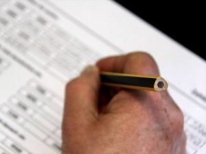 Eine Person schreibt mit einem Bleistift auf ein Stück Papier