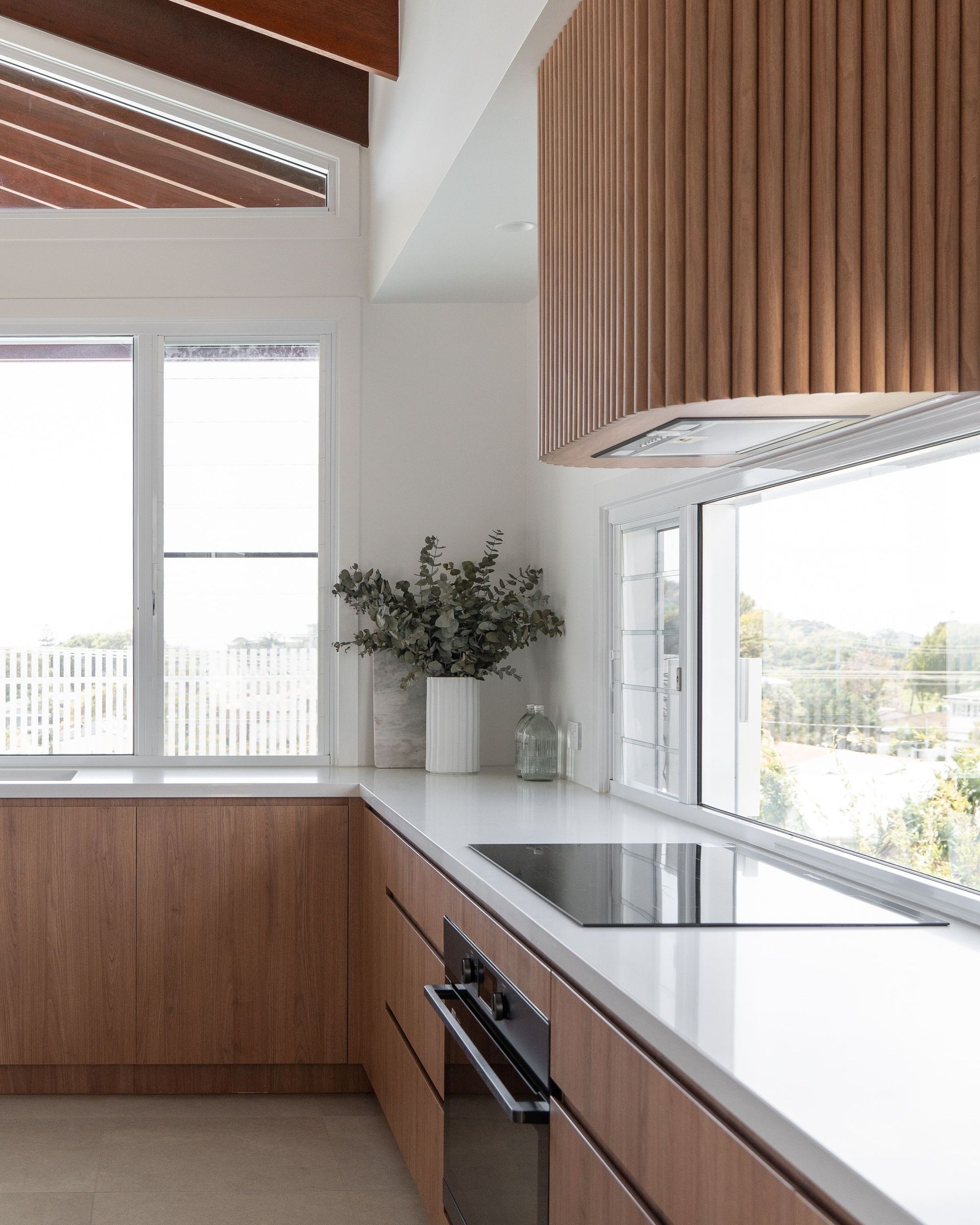 A kitchen with wooden cabinets , a stove top oven , and a window.