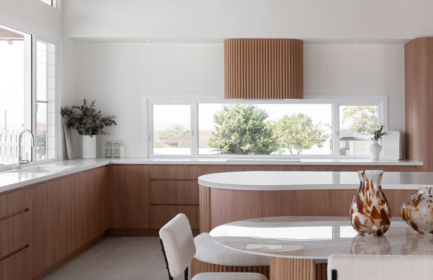 A Kitchen With White Cabinets and Stools and a Large Island — Hot Rock Granite In Burleigh Heads, QLD