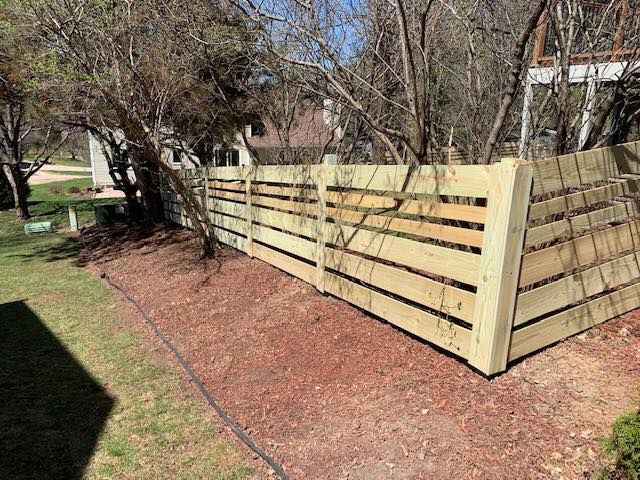 new wood fencing in area with many trees