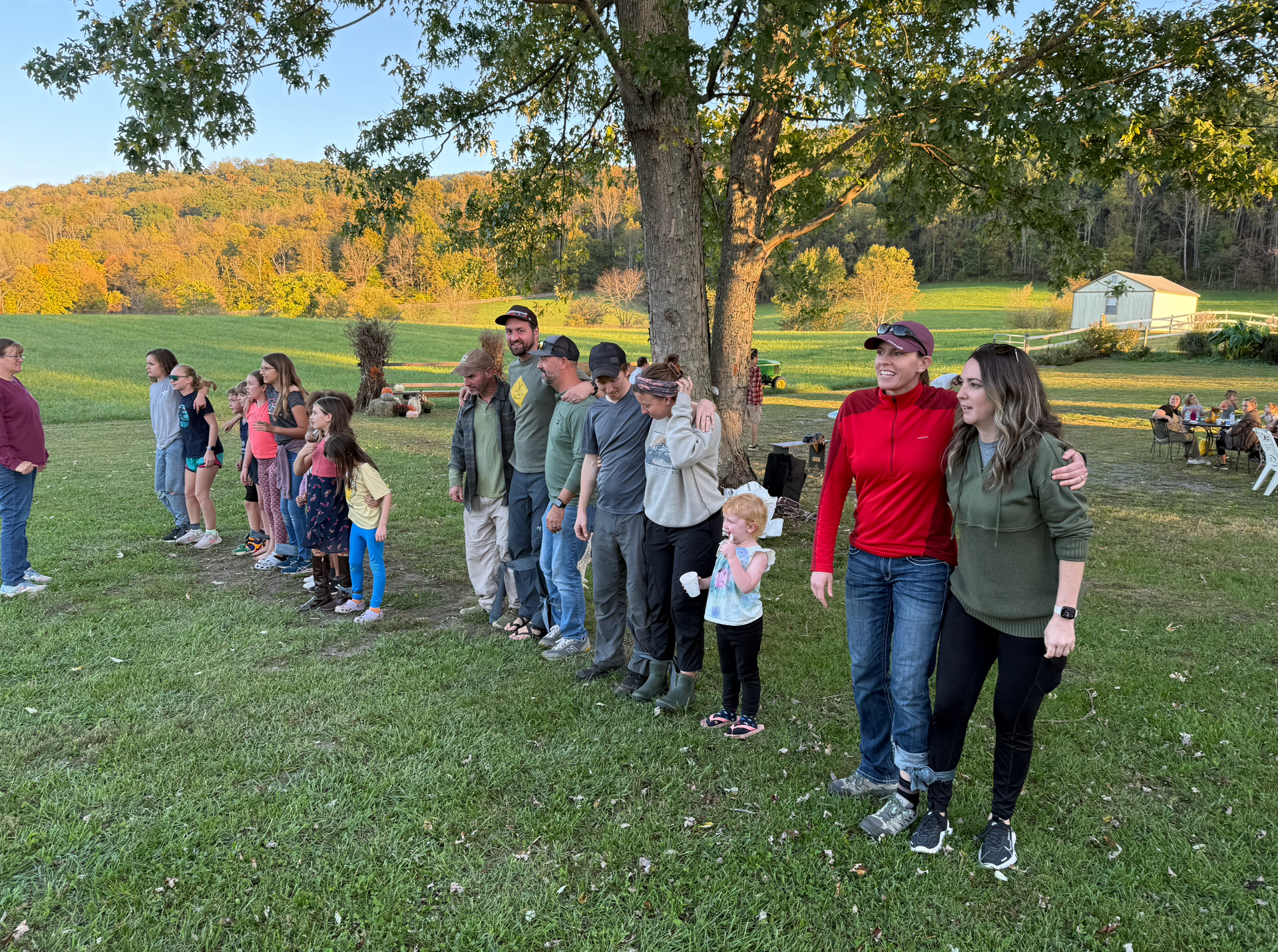 A group of people are standing in a line in a grassy field ready to play games