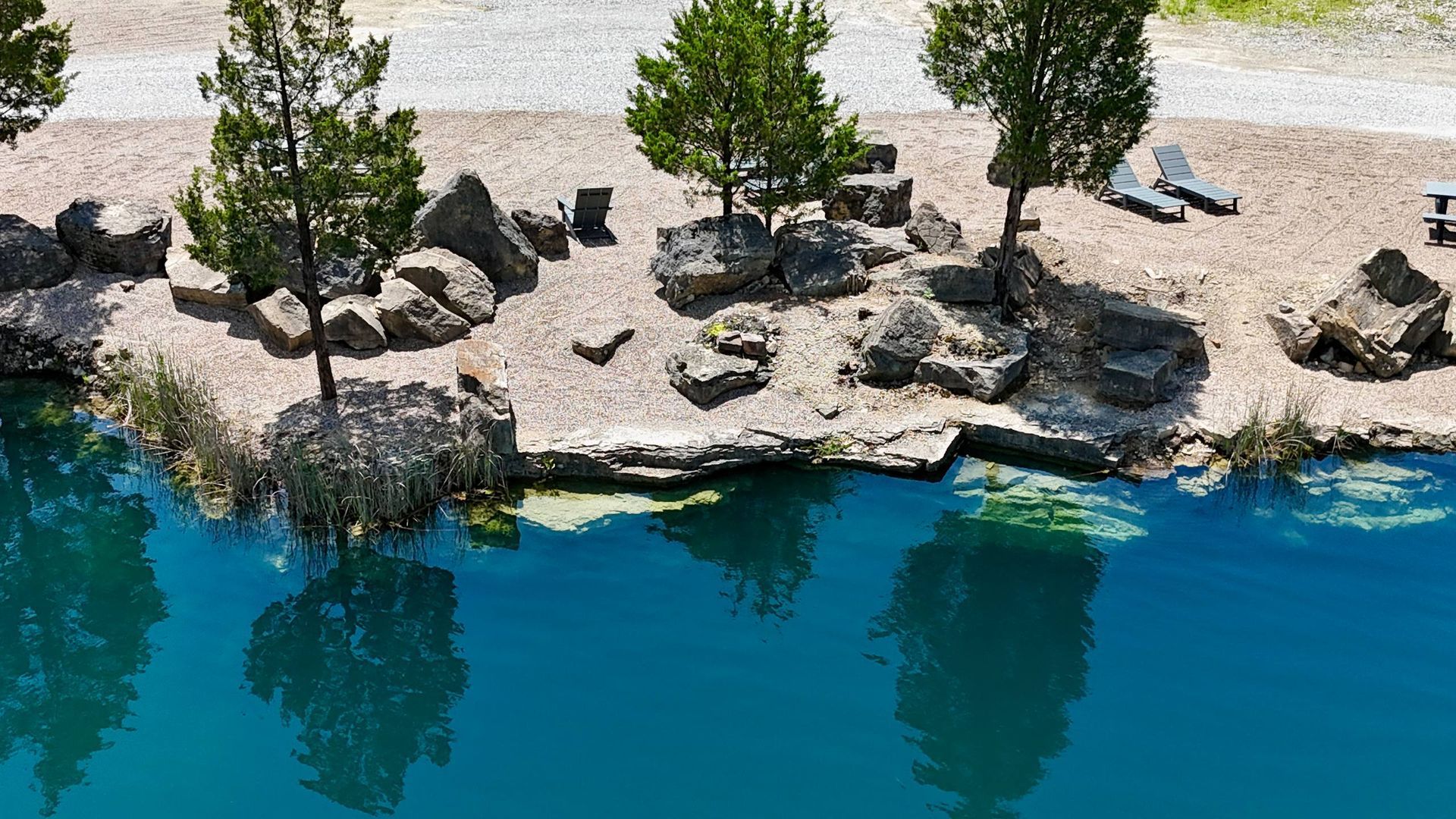 Rocky shoreline with small trees beside bright turquoise water