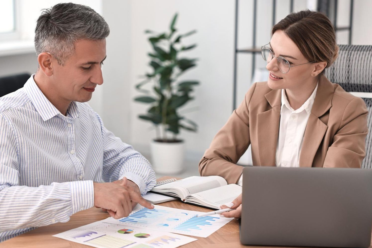 Man and woman reviewing charts at a desk, in an office.