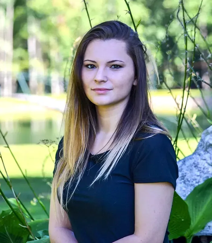 Woman with ombre hair, standing outside, smiling, in a black shirt.