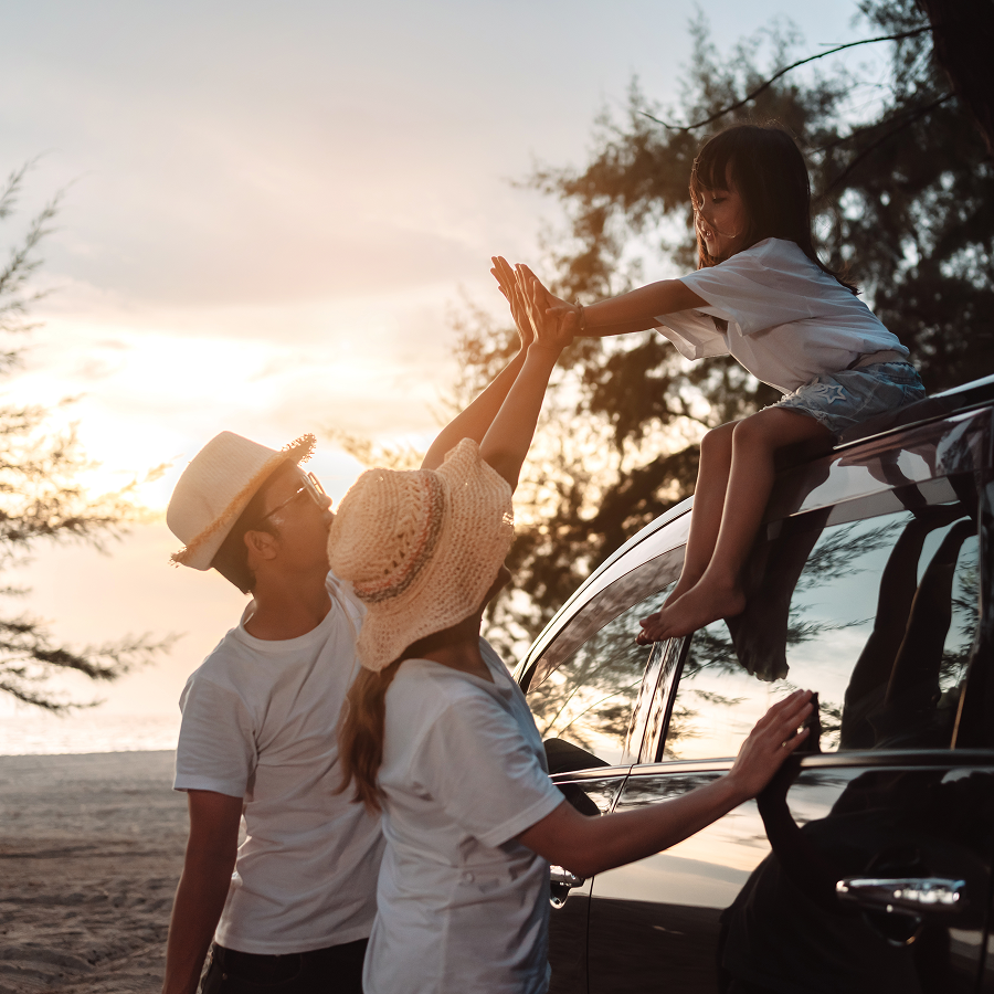 A woman and a child are giving each other a high five while sitting on the roof of a car.