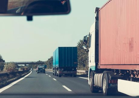 A truck is driving down a highway next to another truck.