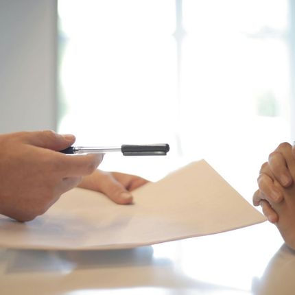 A person is holding a pen over a piece of paper