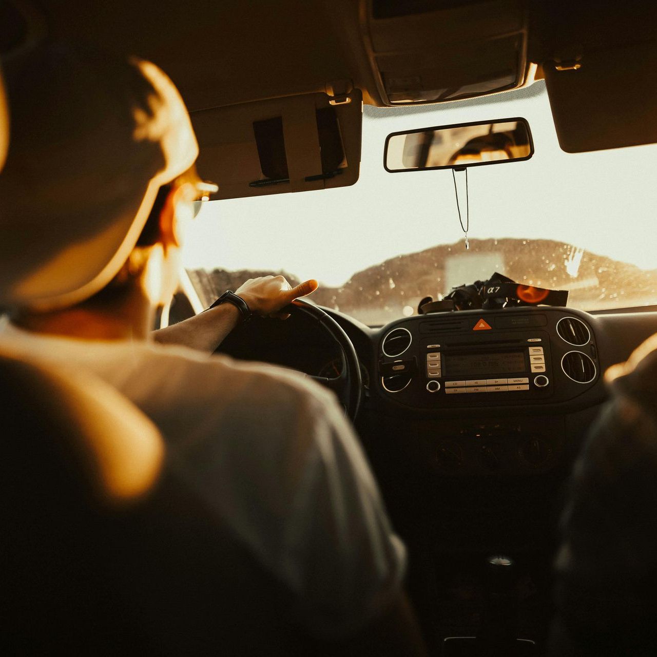 A man in a hat is driving a car