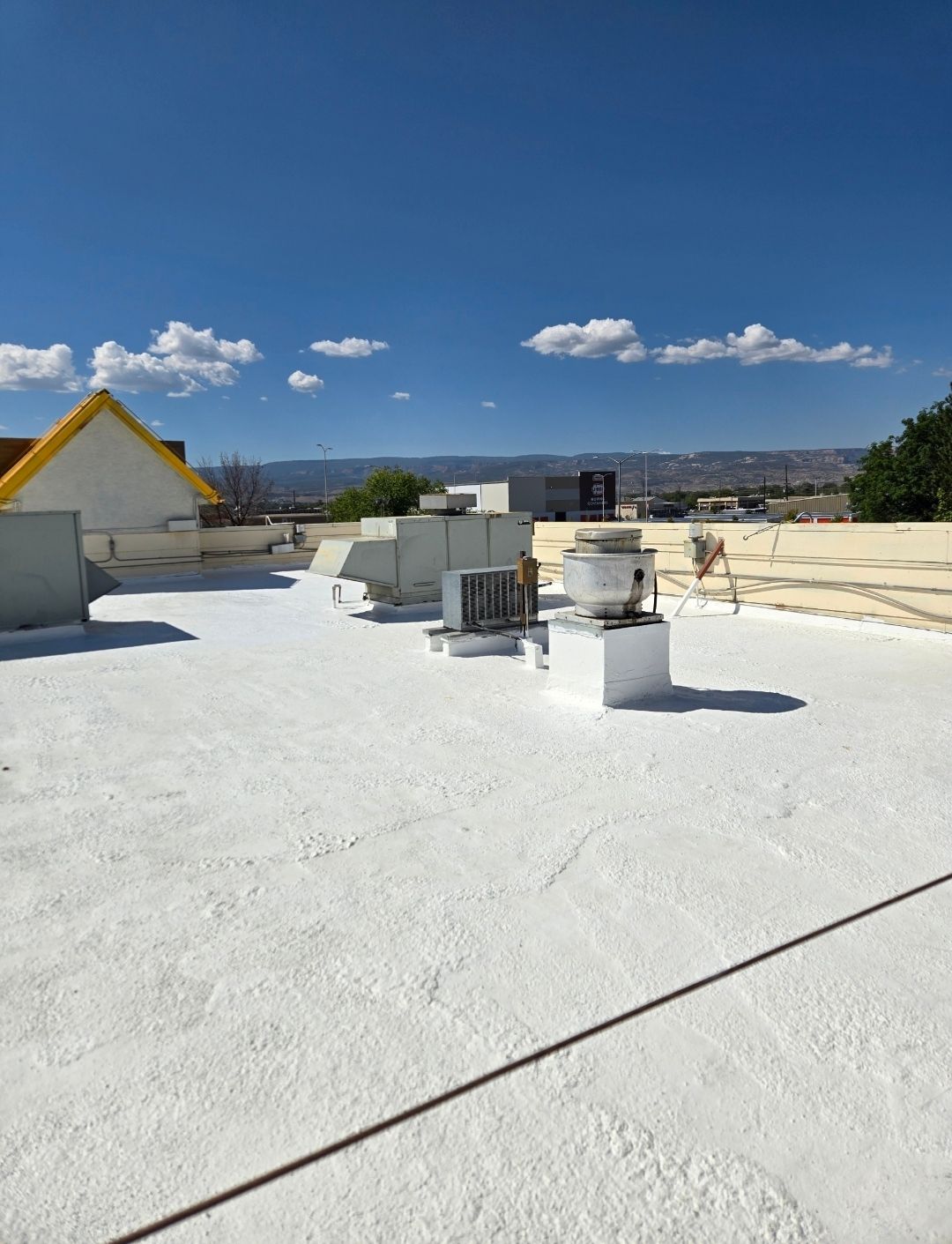 A white roof with a yellow roof in the background