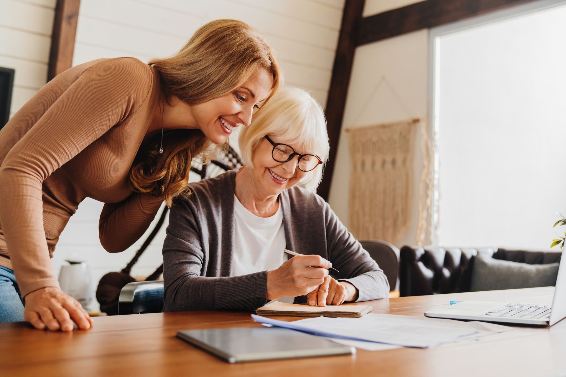 Two people review estate planning documents together at a table with a laptop nearby.