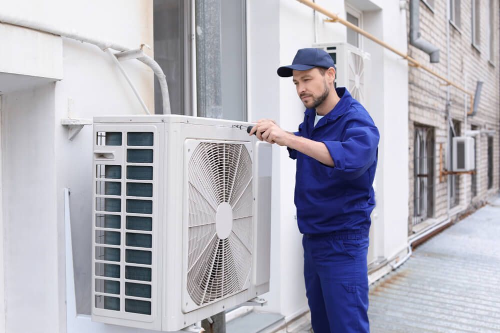 Technician Repairing Air Conditioner Outdoors  —  HVAC Systems in Mudgee, NSW