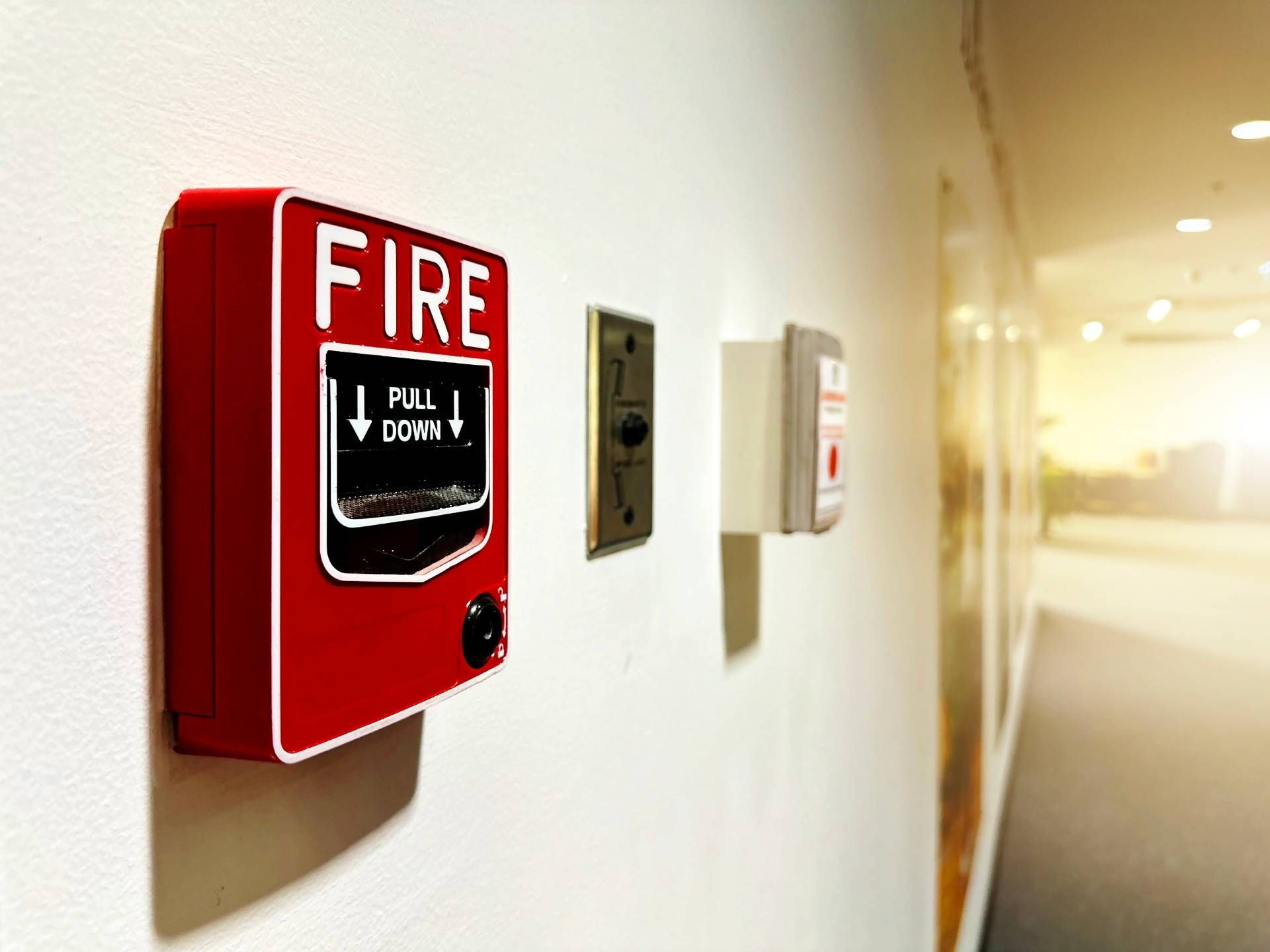 Red fire alarm pull station mounted on a wall in a hallway