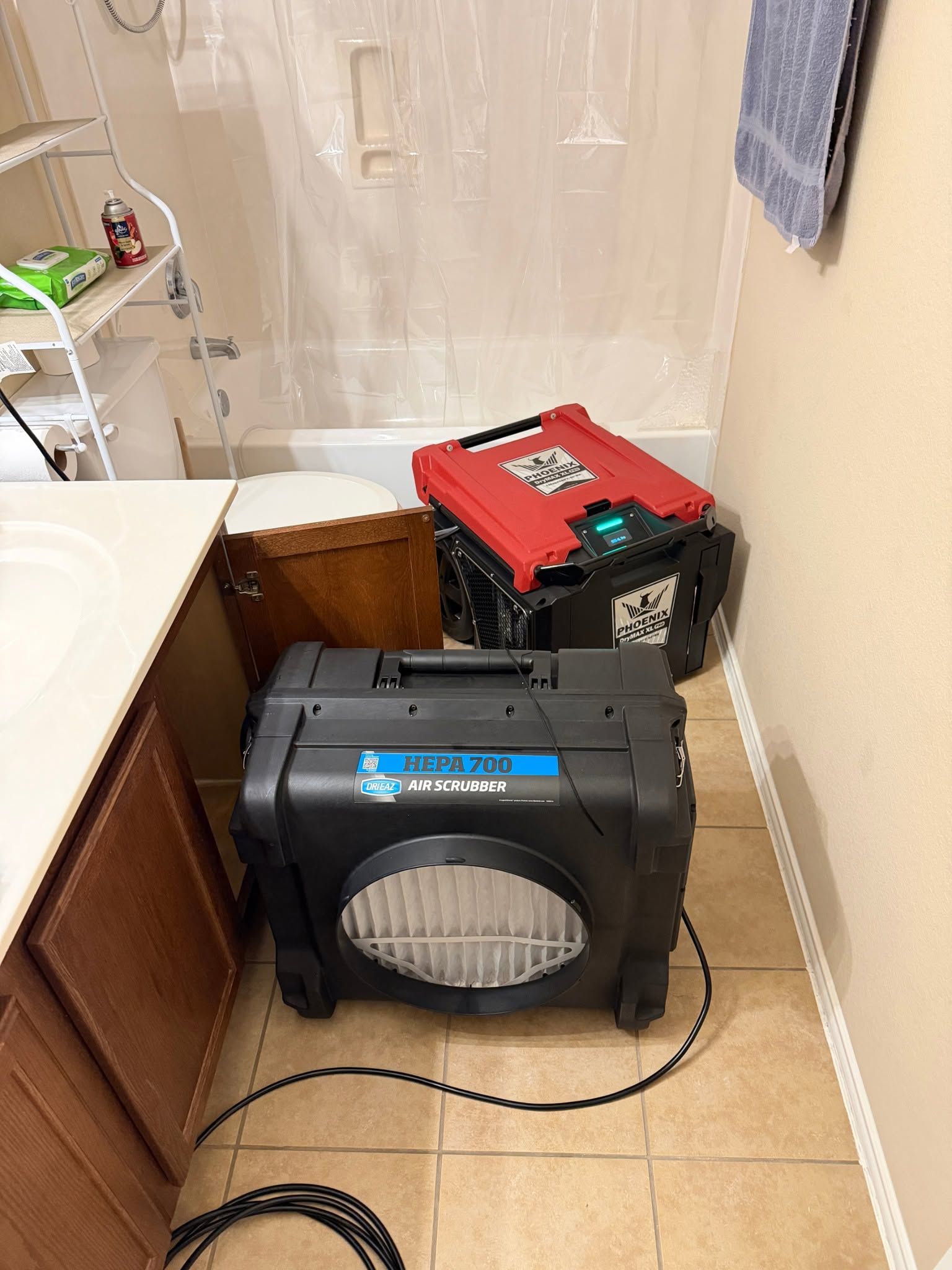 Two portable pet crates in a narrow room, one black and one red, with a power cord on the floor.