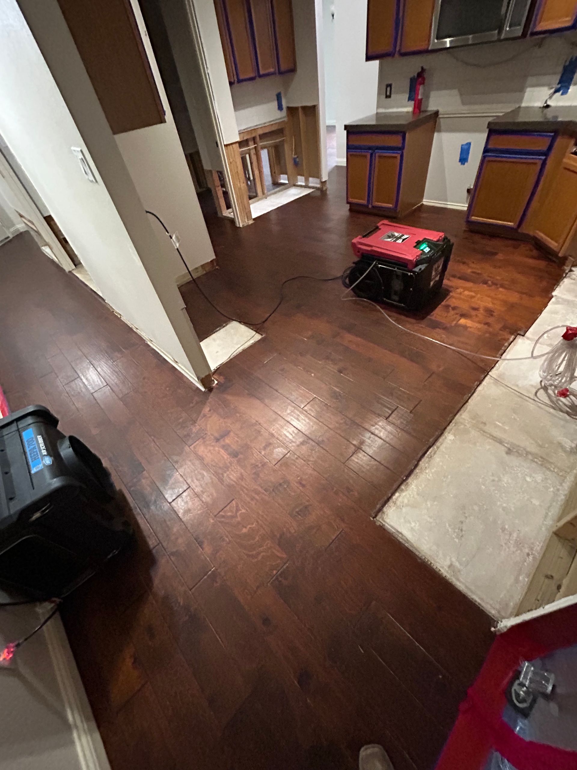 Hallway with dark wood floors, scattered boxes, and a red-and-black portable generator near stairs