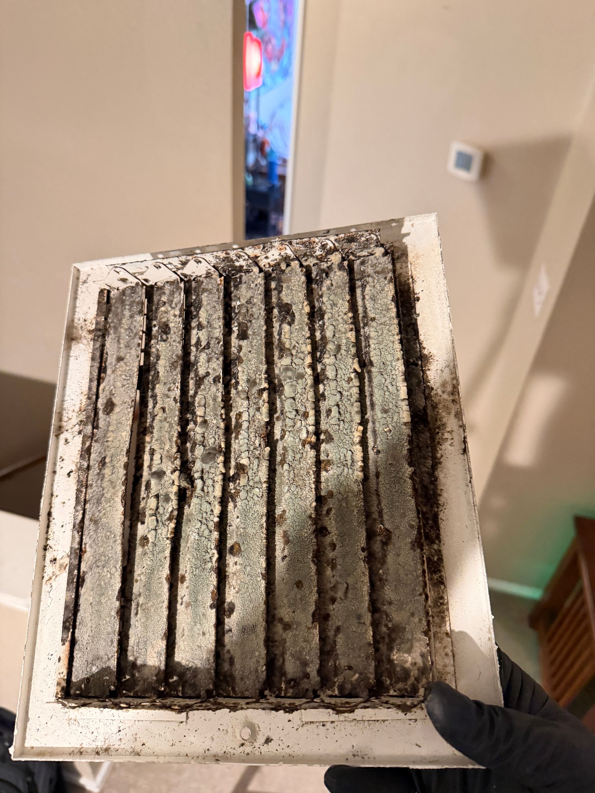 Dirty air filter with black dust streaks held indoors