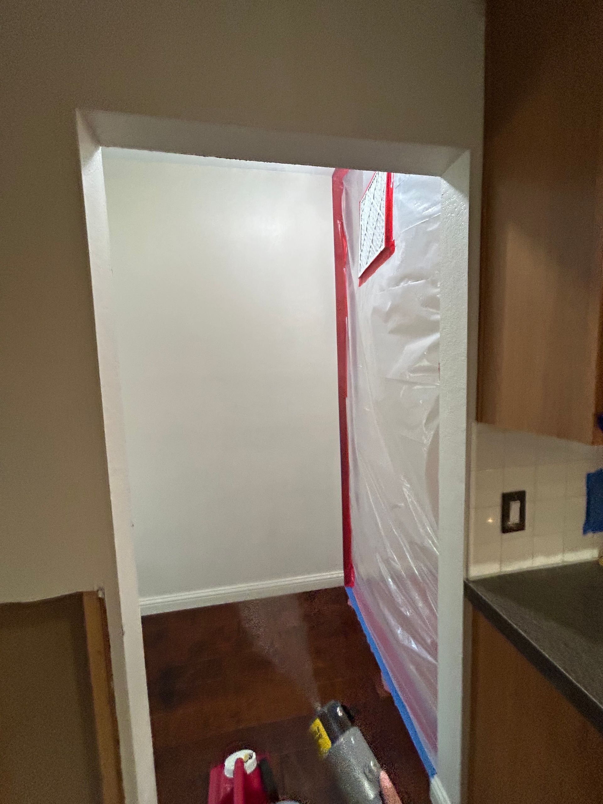 Hallway doorway sealed with white plastic sheeting and red tape during renovation