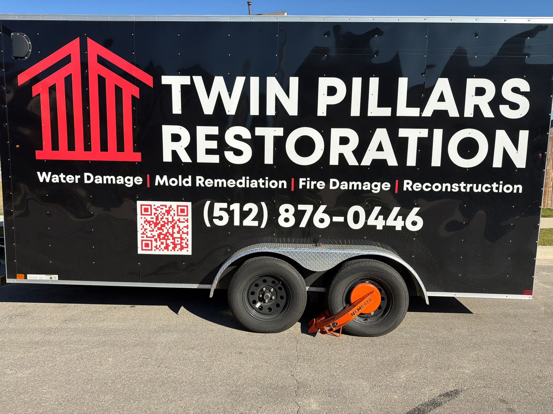 Black trailer for Twin Pillars Restoration with red logo, white text, and phone number on the side.
