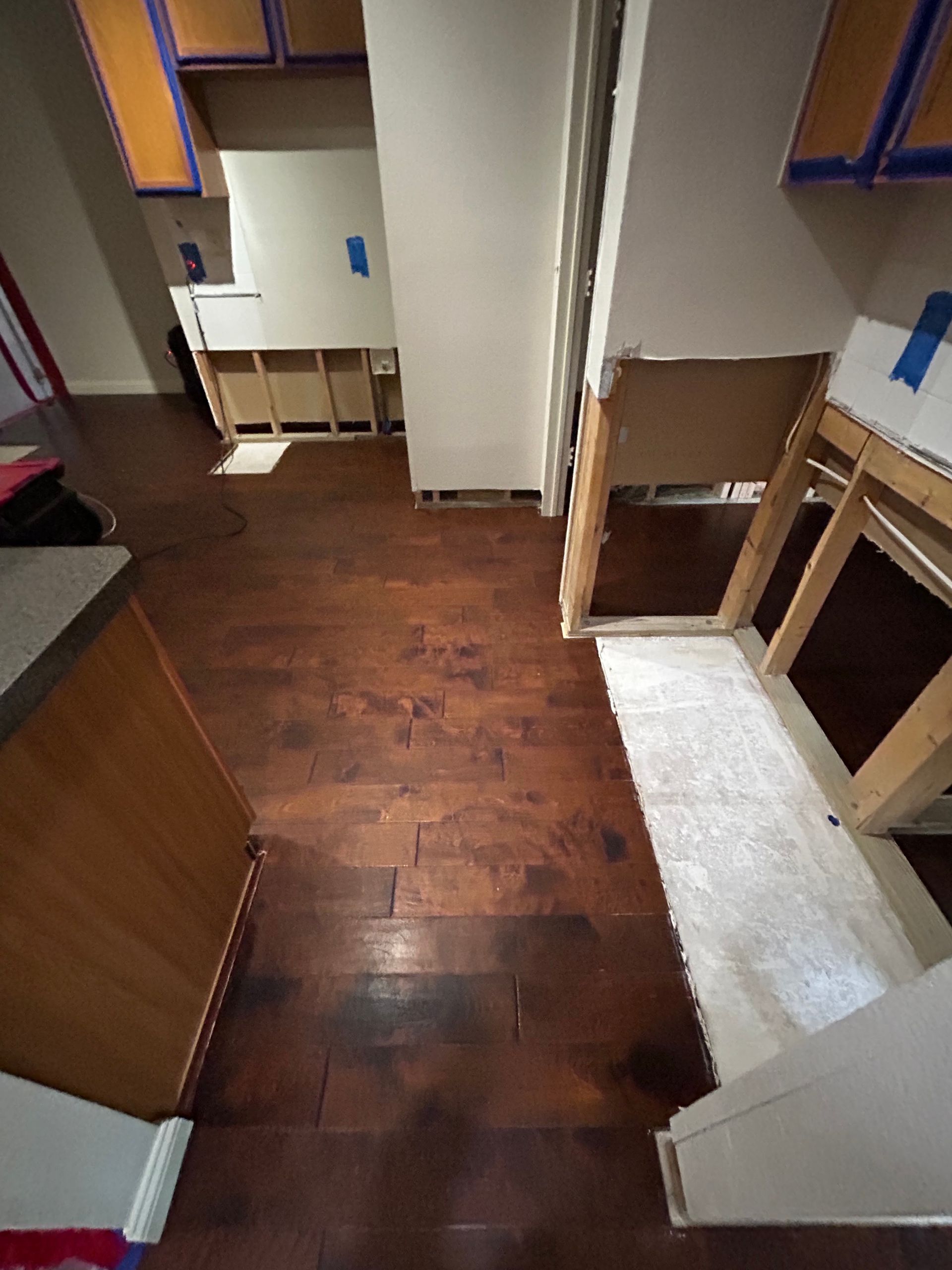 Narrow hallway with wood floors, white walls, and built-in shelves on both sides.