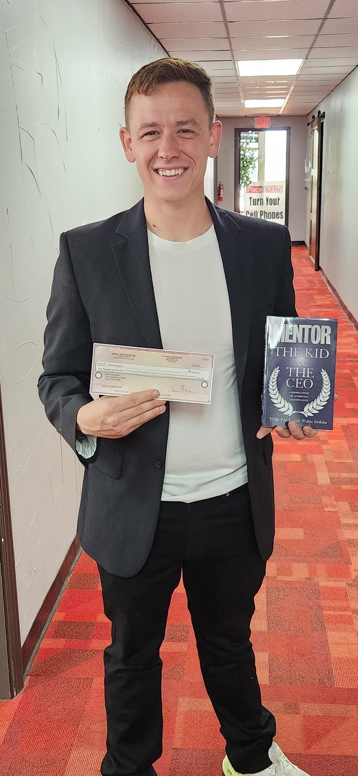 A man in a suit is standing in a hallway holding a book.