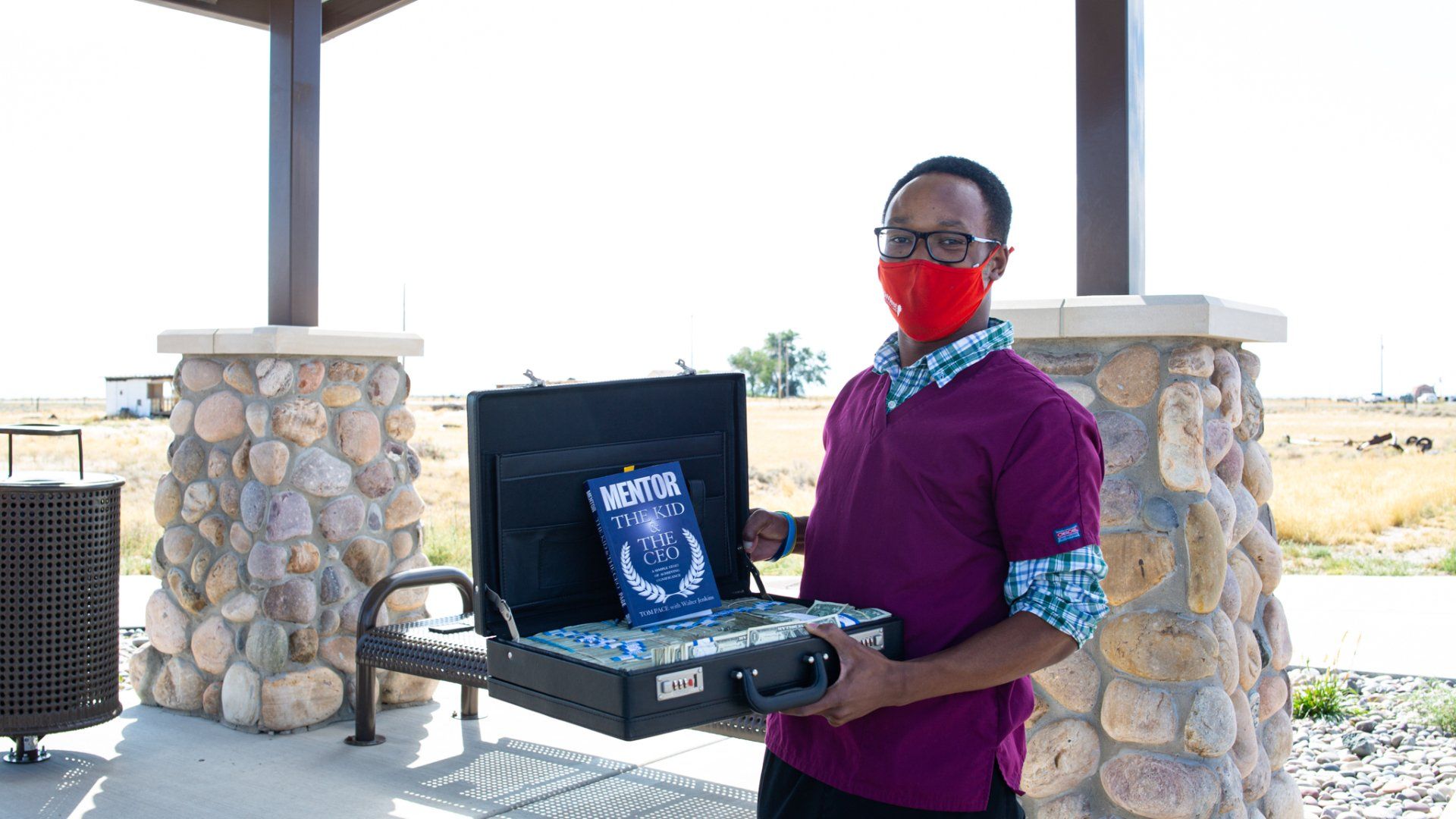 A man wearing a red mask is holding a briefcase.