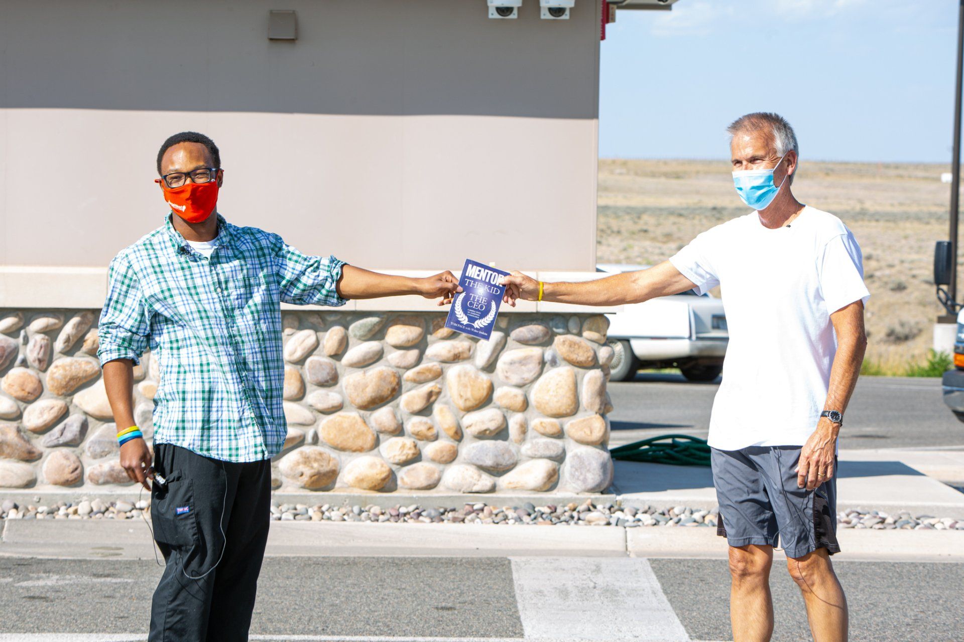Two men wearing face masks are standing next to each other on a street.