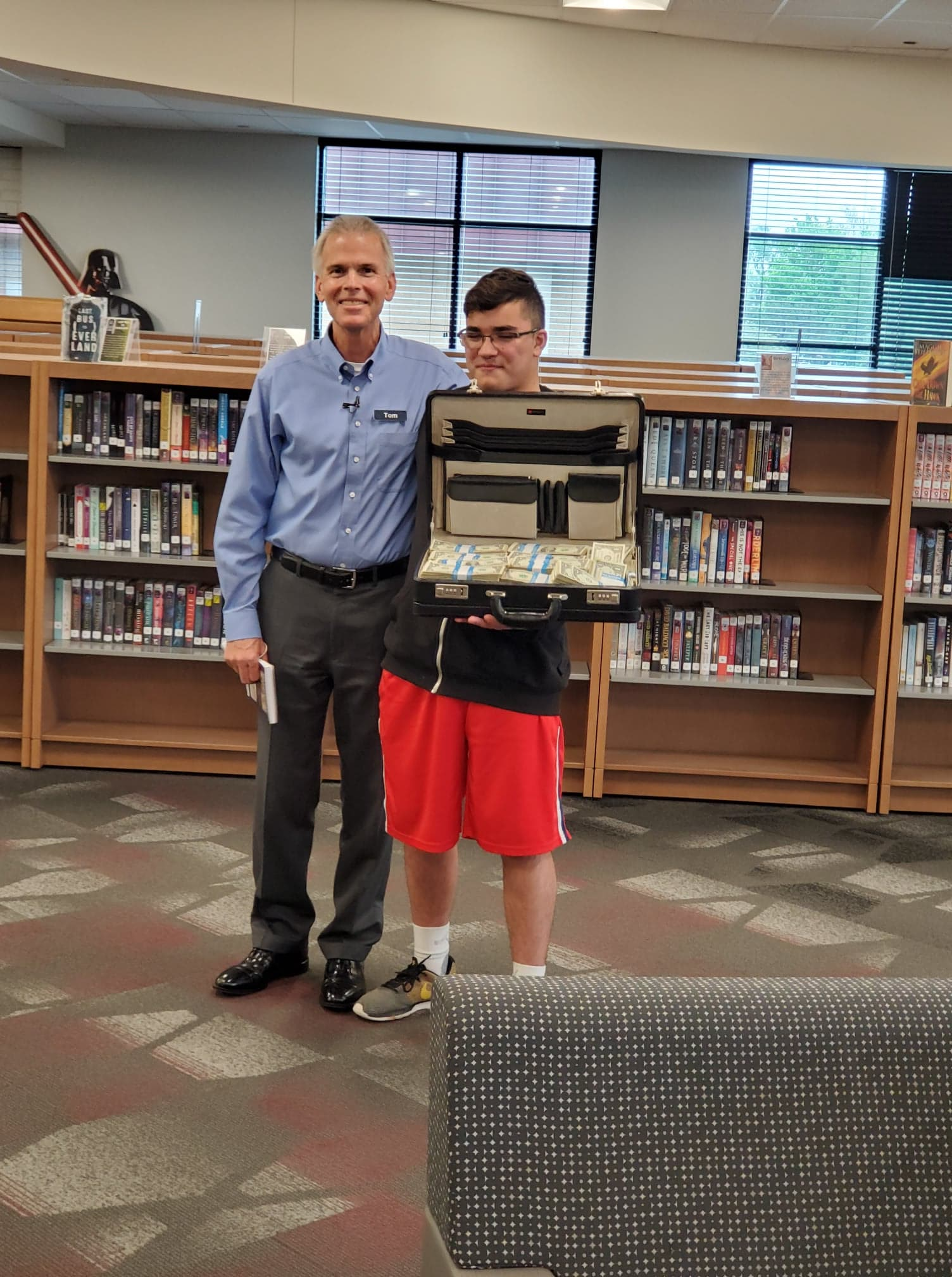 A man standing next to a boy holding a briefcase full of money