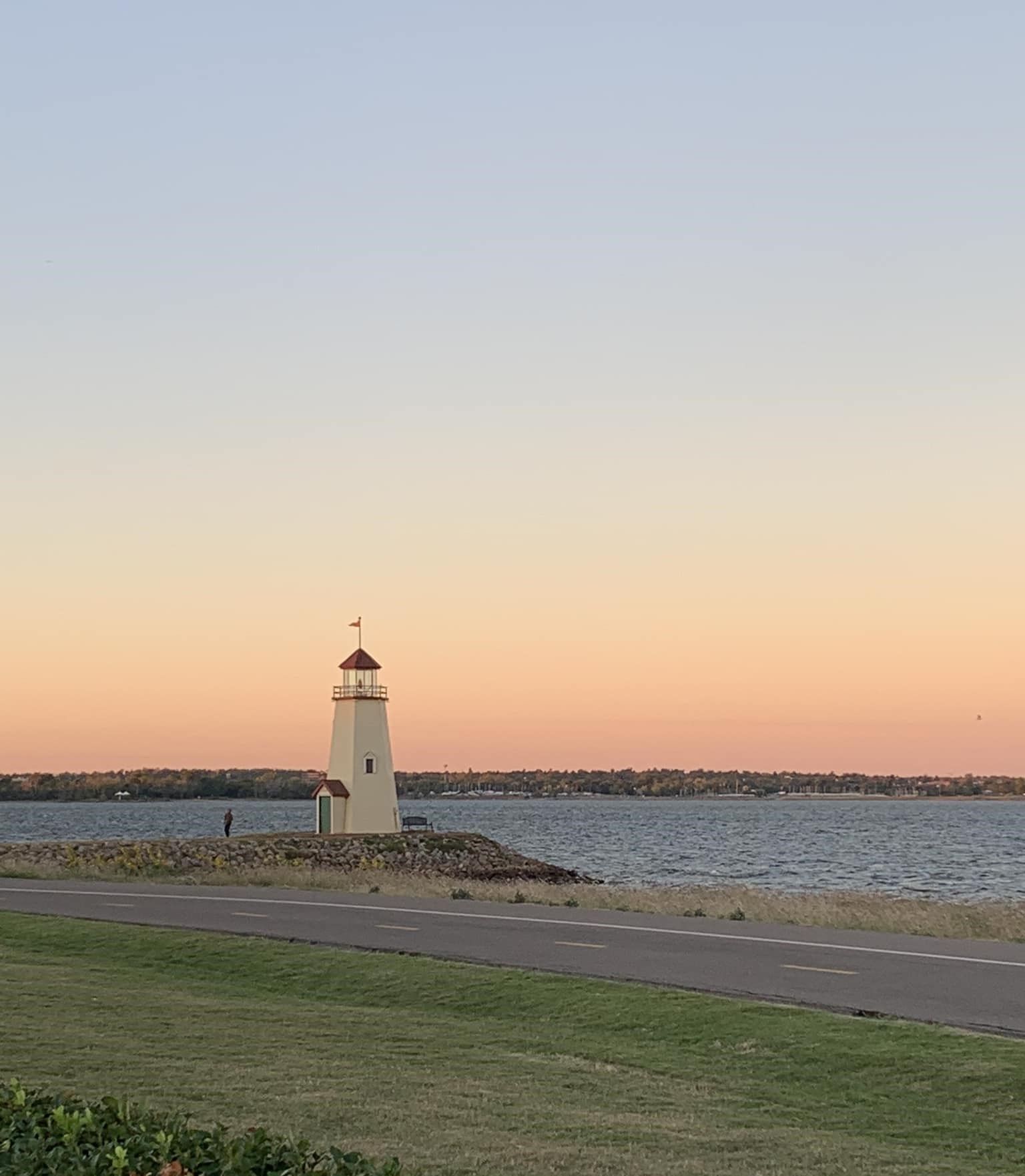 A lighthouse on the shore of a lake at sunset
