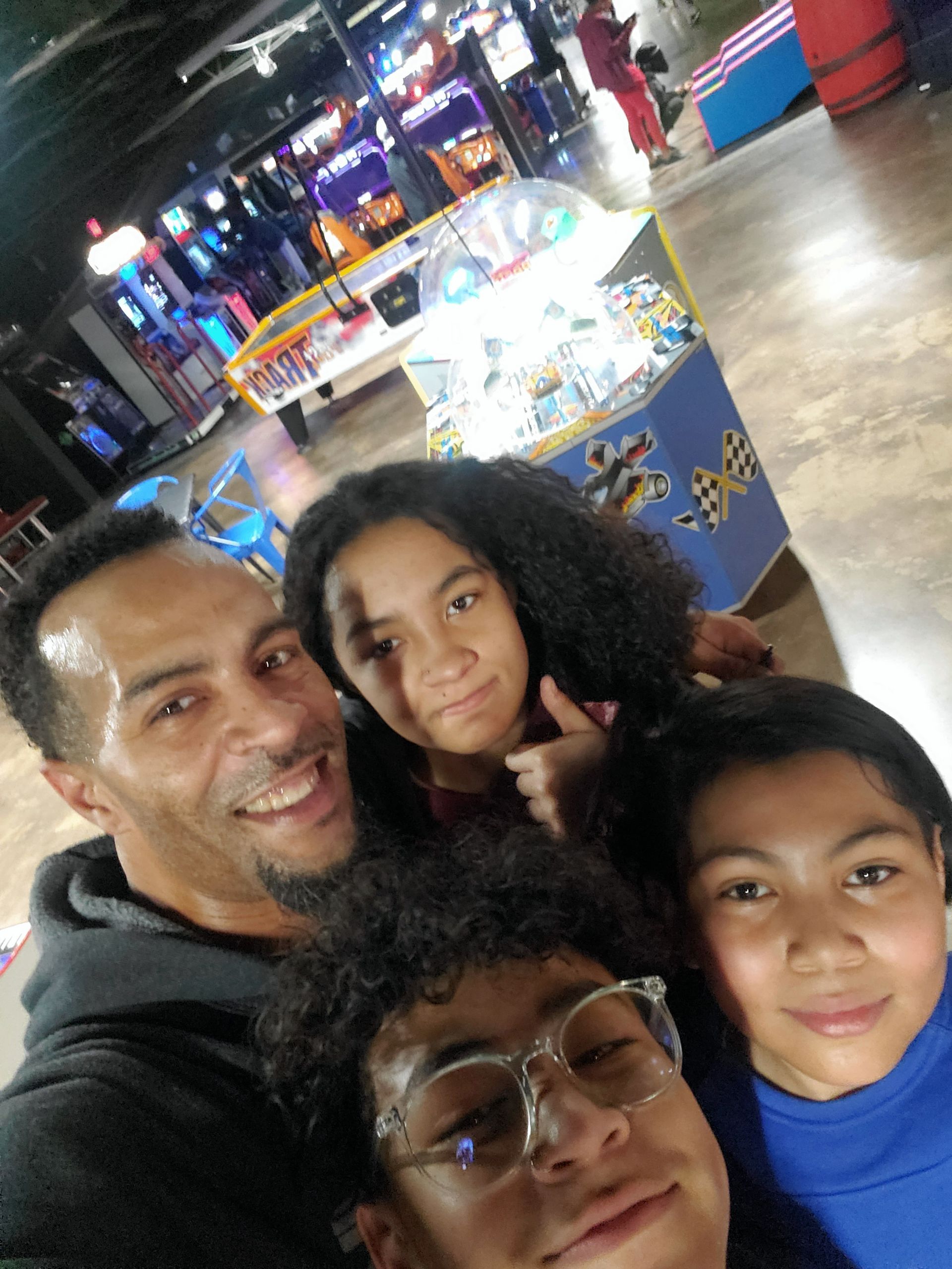 A man and three children are posing for a picture in an arcade.