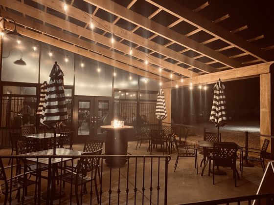 A patio with tables and chairs and umbrellas at night.