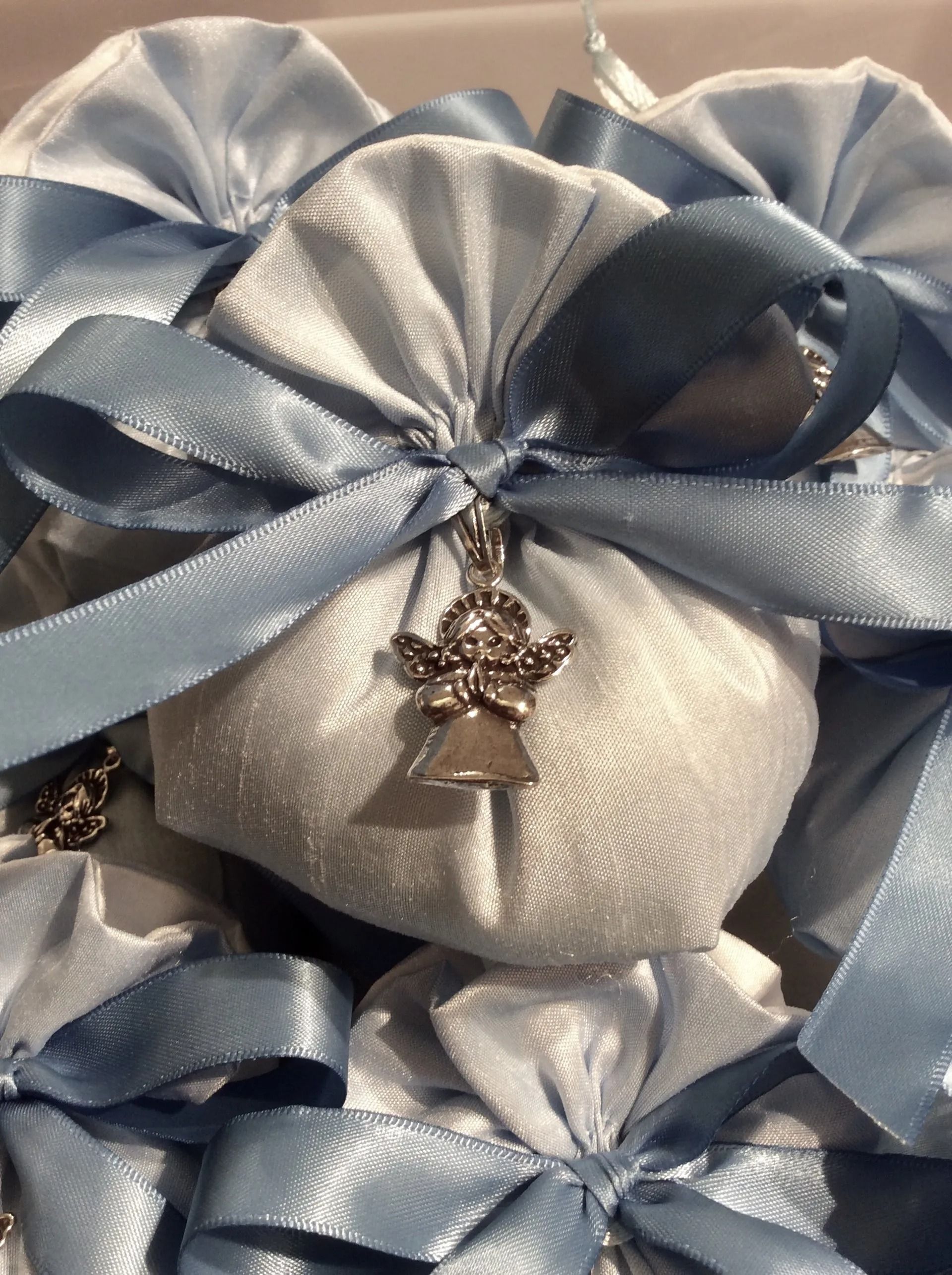 Fiocco regalo in raso argento e blu con un piccolo ciondolo a forma di orsetto al centro.