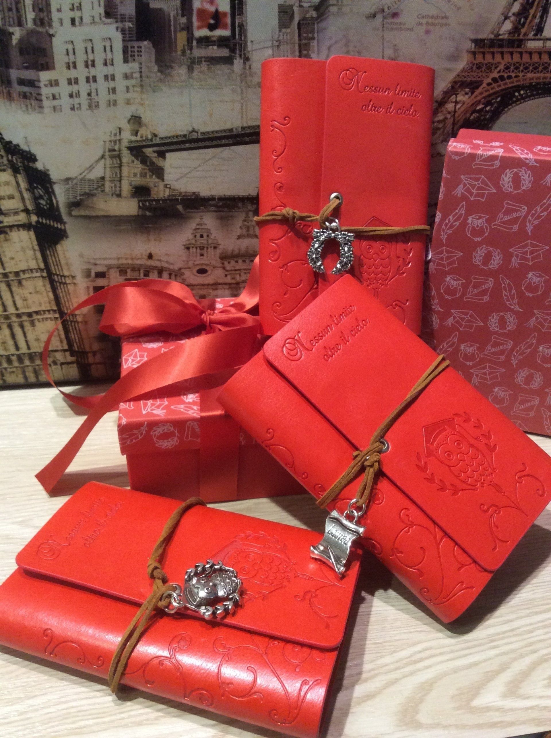 Scatole regalo rosse avvolte con nastri e fermagli decorativi su una superficie di legno.