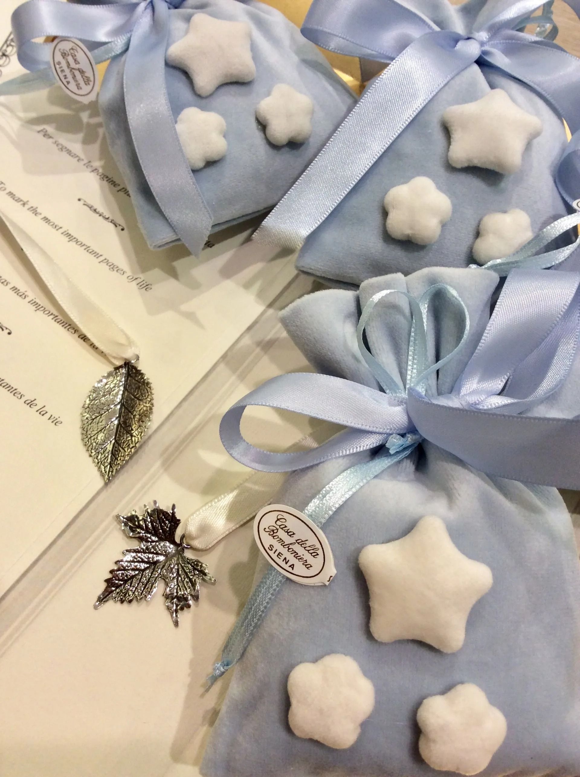 Sacchetti regalo blu a forma di stella con dolcetti bianchi a forma di stella e fiocchi di nastro su un tavolo con etichette di carta.