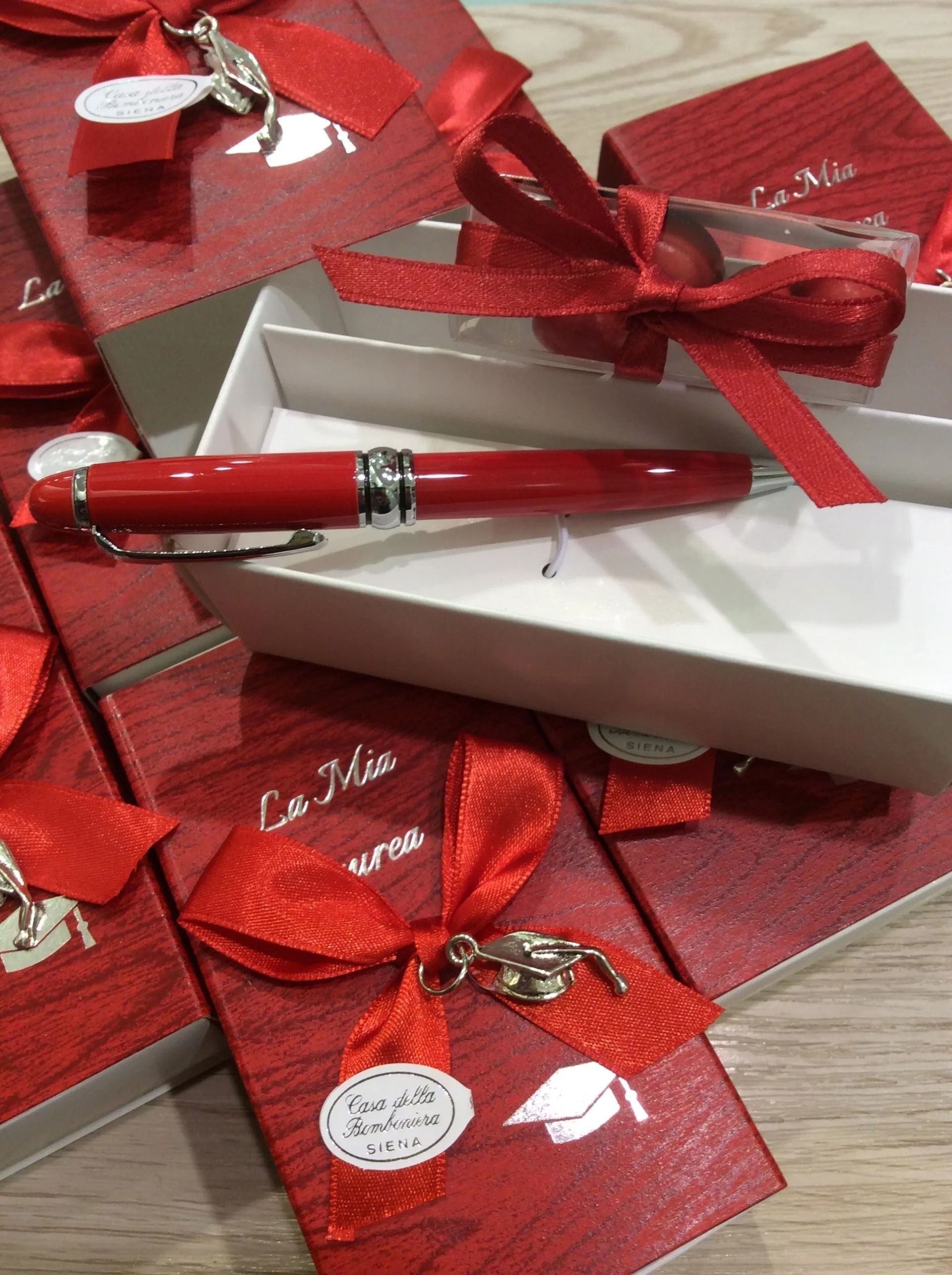 Penna stilografica rossa in una scatola regalo bianca con fiocchi rossi e carta da regalo su un tavolo.