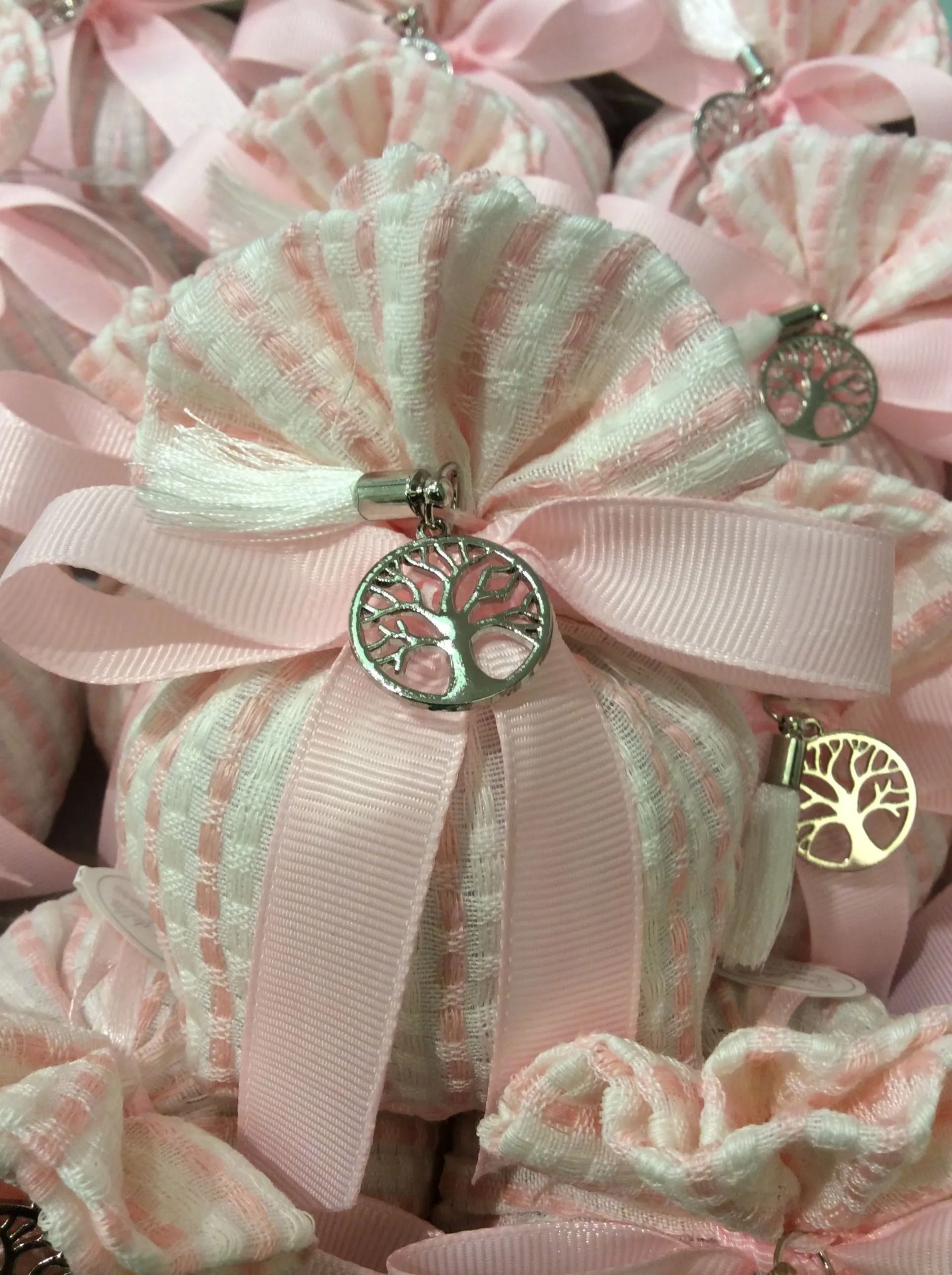 Sacchetti regalo rosa e verde menta con nastro bianco e ciondoli a forma di albero impilati uno sull'altro