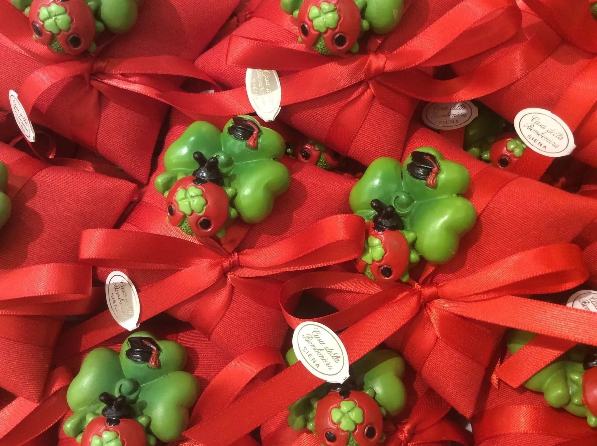 Fiocchi regalo rossi con piccole coccinelle decorative verdi e rosse su sfondo rosso