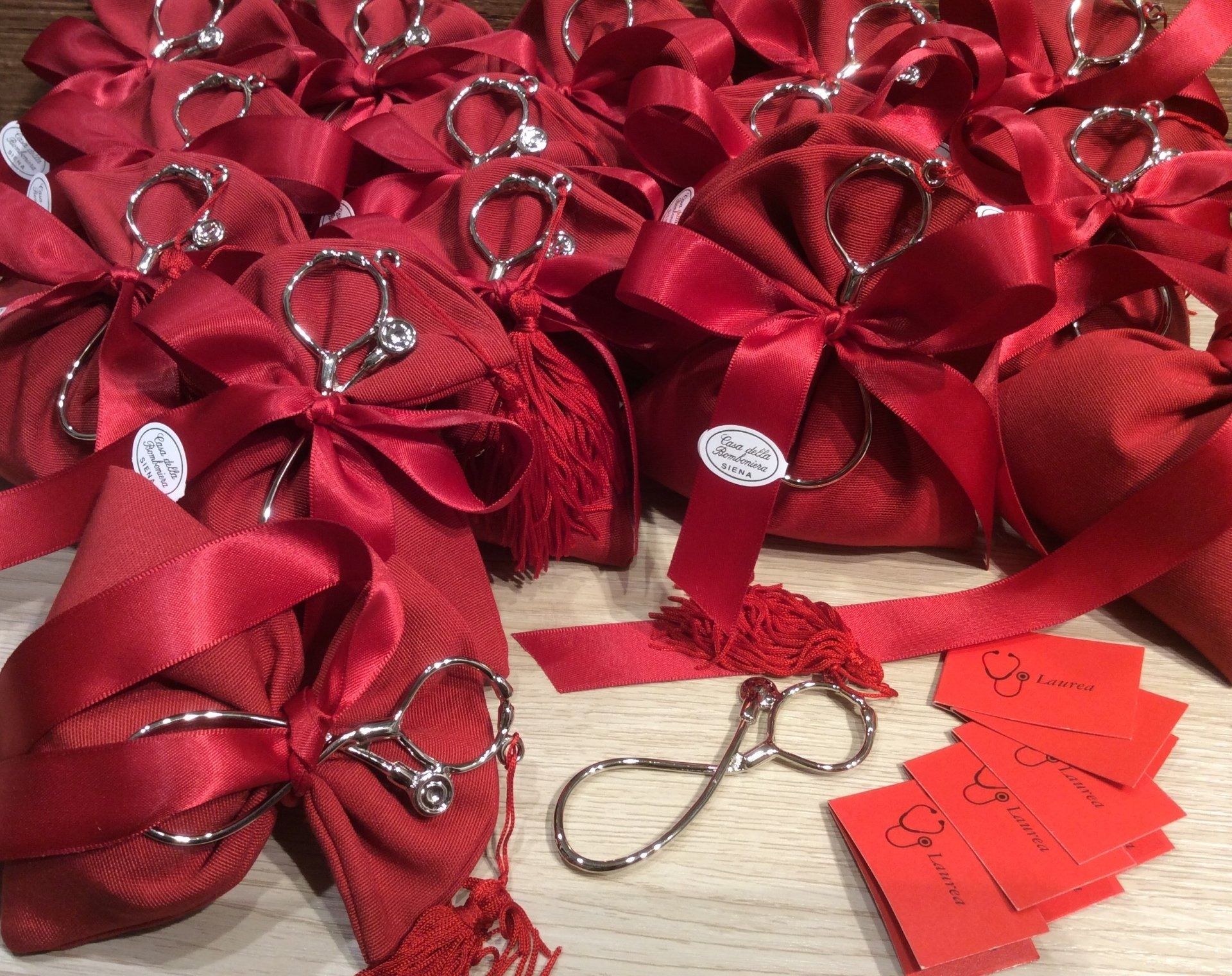 Sacchetti regalo rossi con fiocchi e targhette a forma di cuore argentate, oltre a cartellini rossi con il prezzo su un tavolo.